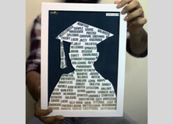 guy holding a white frame with graudation silhouette and custom name printed at top