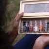 girl opening a pine wood box with multiple mini message bottles inside it