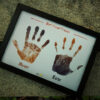 hand prints and name edited in a black a4 frame placed on a park bench
