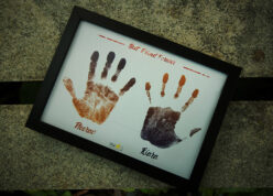 hand prints and name edited in a black a4 frame placed on a park bench