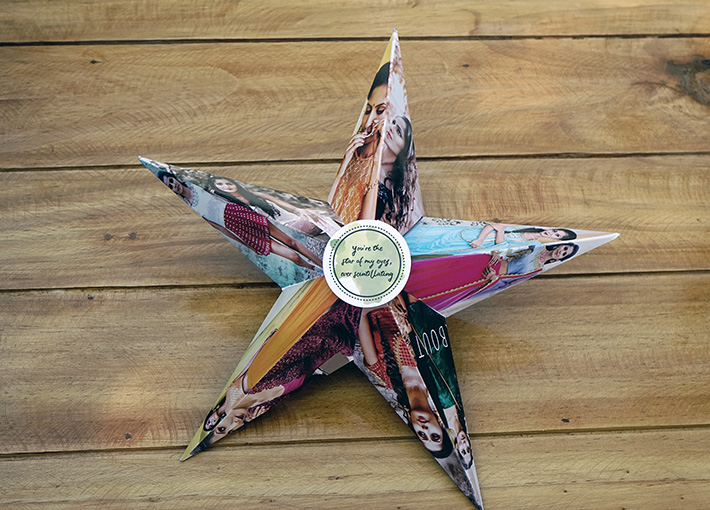 A 3D star with pictures of a girl one on each side of a leg, with a quote card in the center, placed on a wooden table.