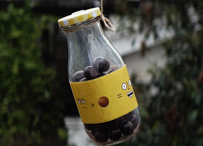 mini bottle with chocolates inside it and yellow sticker with doodles