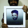 guy holding a white square frame smiling at his logo face and name