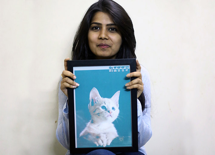 girl holding her pet's portrait in her hands and smiling
