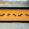 Black rectangle with morse code name formed with nuts and bolts
