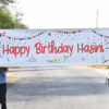 Two persons holding Happy Birthday name surprise banner