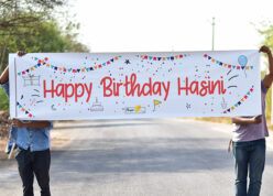 Two persons holding Happy Birthday name surprise banner