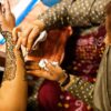 lady mehendi artist putting mehendi to bride in indian traditional event