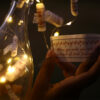 girl opening a custom message note with fingers in a warm white light from string