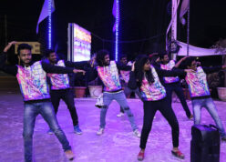Group of stylish dancers in dress code grooving to music and performing flashmob at drive-in