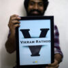 guy holding black frame with his name printed on it