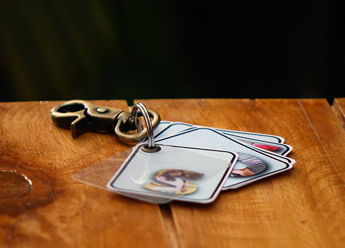 Vintage style key holder to a key chain with pictures and letters of a name on a wooden table.