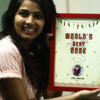 girl holding a red a4 frame with world's best cook and her name printed on it