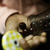 Girl taking chocolates into hands from little transparent bottle