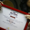 girl holding a best girlfriend certificate red frame and smiling in a room