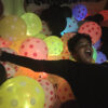 Boy falling on LED ballons in a room with surprised face